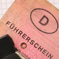Niemieckie prawo jazdy "Führerschein" z literą "D" w owalu, na tle kratkowanej kartki.